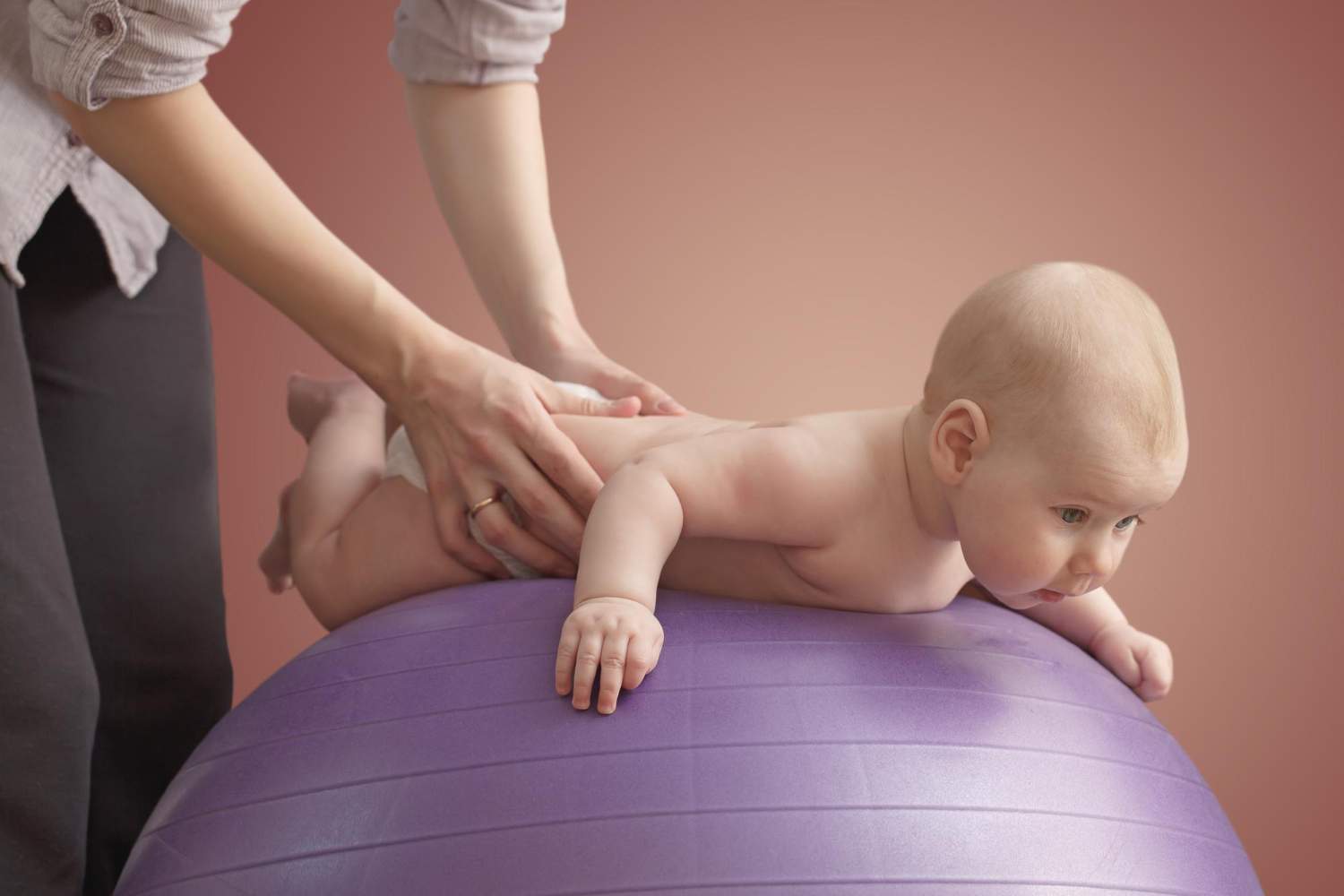 mujer dando masajes su bebe bola purpura fondo color